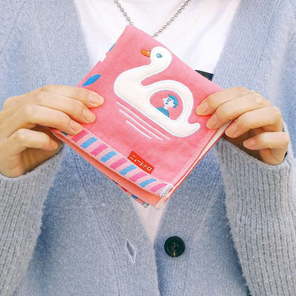 A person holding a folded Hightide Hand Towel - Swan Boat (1 pc) 