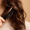 L'Artisan Brossier Pure Boar Bristle Brush - Medium (1 pc) - product shown brushing hair.