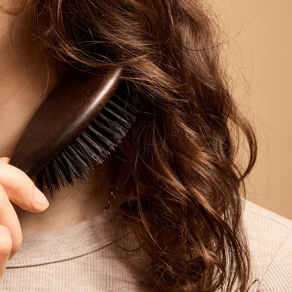 L'Artisan Brossier Pure Boar Bristle Brush - Medium (1 pc) - product shown brushing hair.