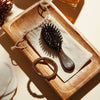 L'Artisan Brossier Pure Boar Bristle Hand Bag Brush (1 pc) - product shown on wooden slab.