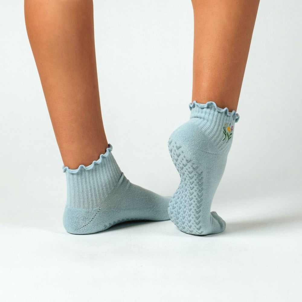 A pair of PikeFit Wildflower Grip Socks shown on feet of model (back and bottom view) - available in S/M and M/L, shown on a person's feet. One sock is shown from the side, the other showing the bottom of the foot.