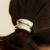 A close-up of a person's dark brown hair tied back withnar’sha Mini Double Arch Metal Ponytail Hair Tie - Silver