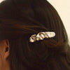 A close-up of a person's dark brown hair secured with a nar’sha Textured Metal Barrette Hair Clip - Silver