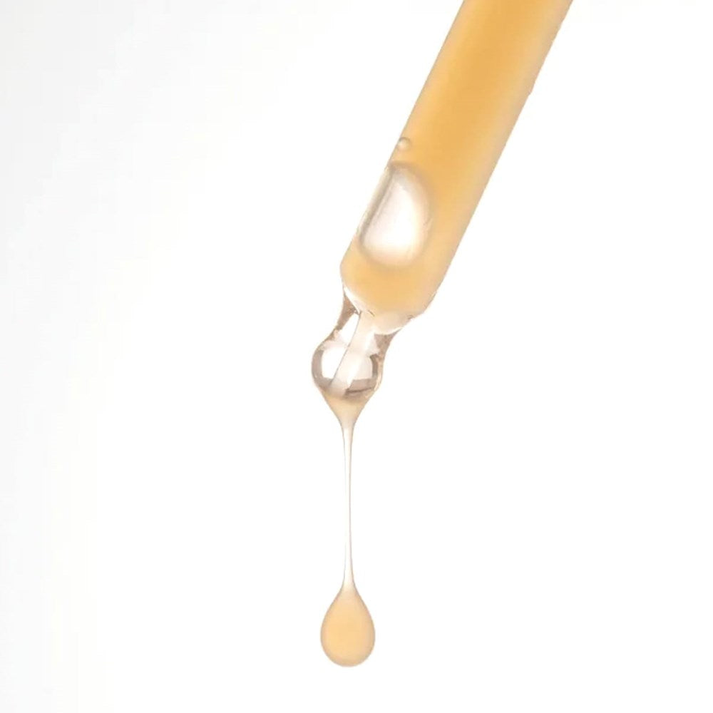 A close-up of a clear glass dropper containing a Dr. Hauschka Hydrating Serum Plus