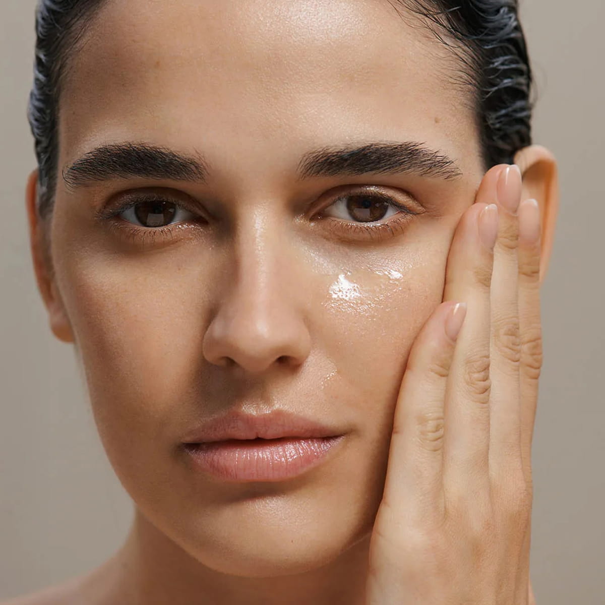 Close-up of a woman applying Dr. Hauschka Hydrating Serum Plus on her cheek