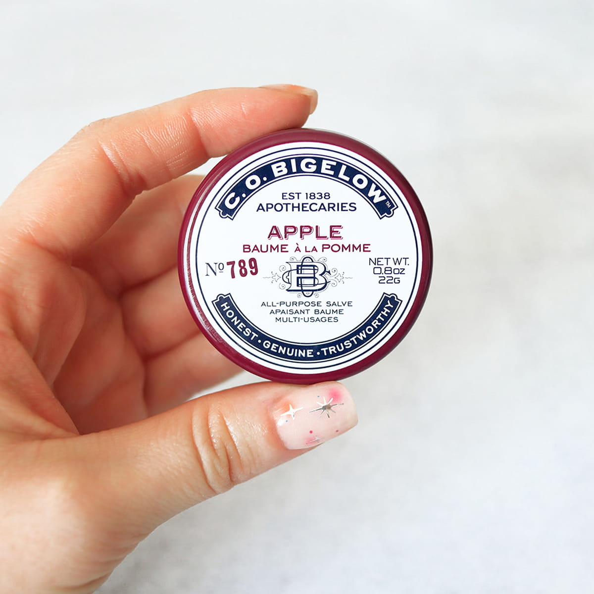 C.O. Bigelow Apple Salve Lip Tin (0.8 oz) - product shown being held in hand 