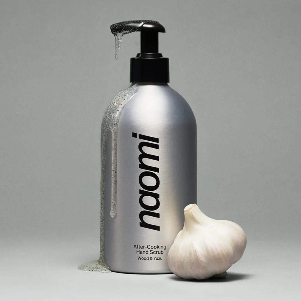 Naomi After-Cooking Hand Scrub - Wood &amp; Yuzu (500 ml) next to a whole garlic bulb