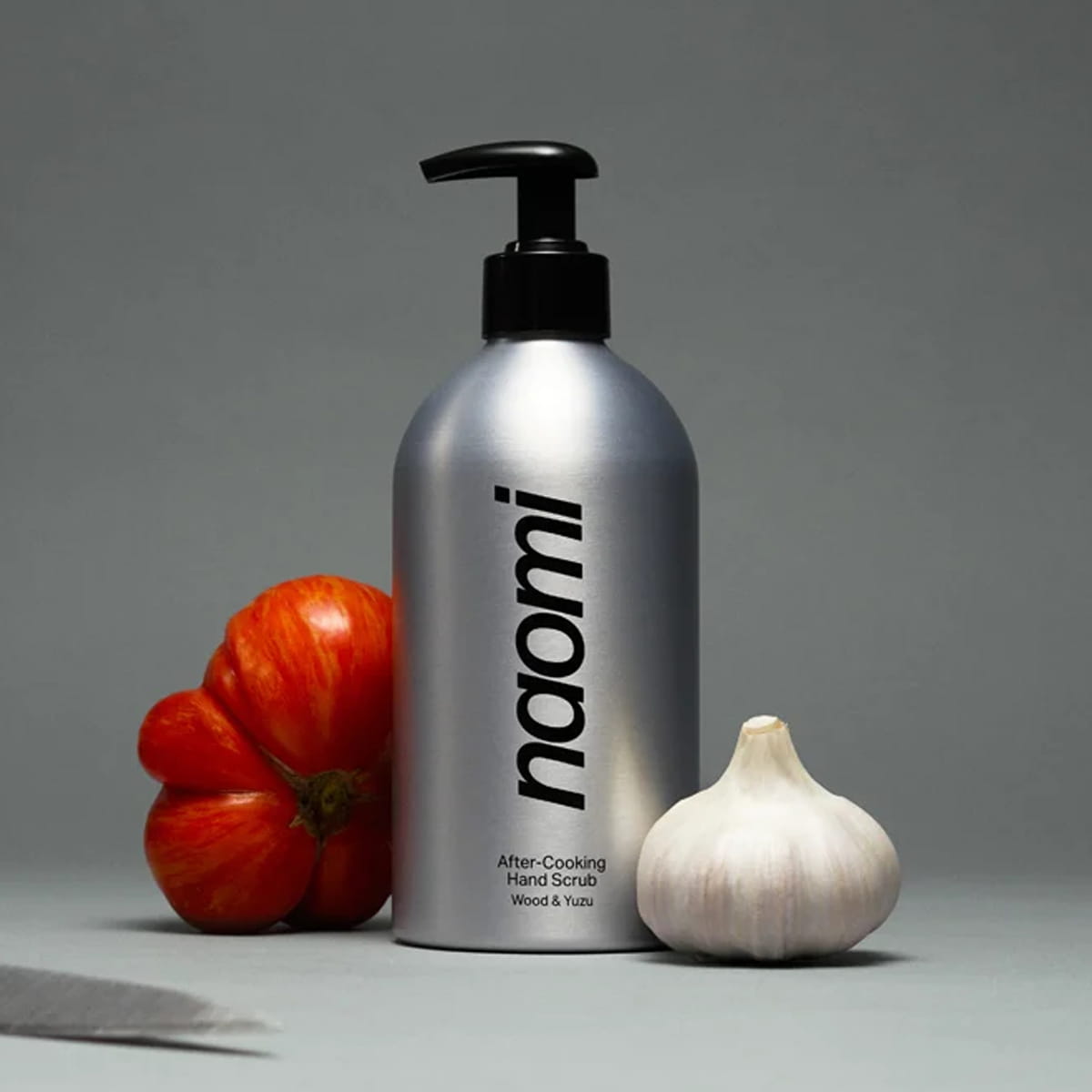 Naomi After-Cooking Hand Scrub - Wood &amp; Yuzu (500 ml) styled with a red tomato and a garlic bulb