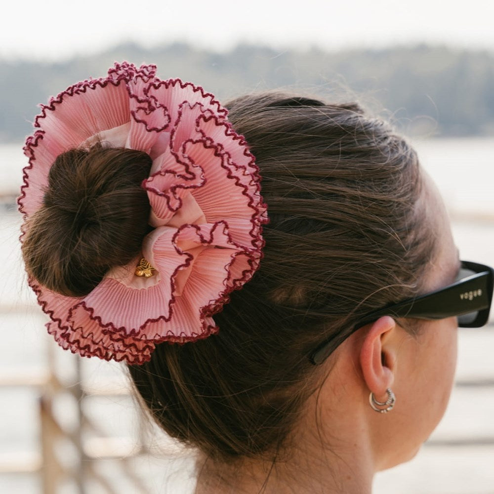 L. Erickson Lilo Scrunchie shown worn in a woman's hair bun. The photo is taken from the side/back, with the woman wearing black sunglasses and hoop earrings, against a softly blurred outdoor background