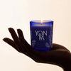 Yon-Ka Lavender Scented Candle held in the palm of a person's hand against a warm off-white background.