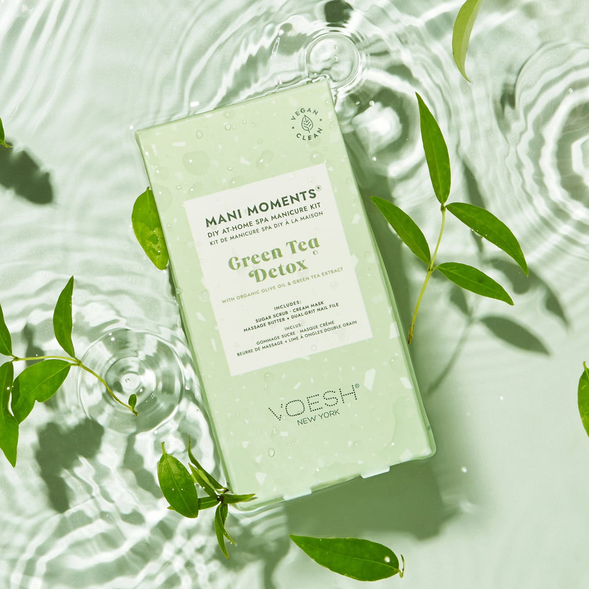 Lifestyle shot top view of VOESH New York Mani Moments - Green Tea Detox box with water and green leaves in background