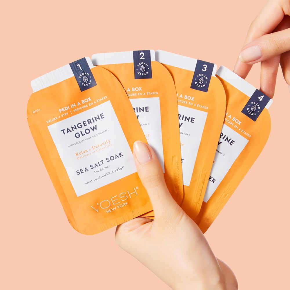 Model holding packets from the VOESH New York Pedi In A Box - Tangerine Glow