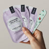 A hand holds packets alongside a holiday nail file from the VOESH New York Mini Mani Set (10 pcs)