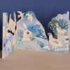 Art Angels close up of front section of die cut card showing bunnies and  other wildlife in winter scene.