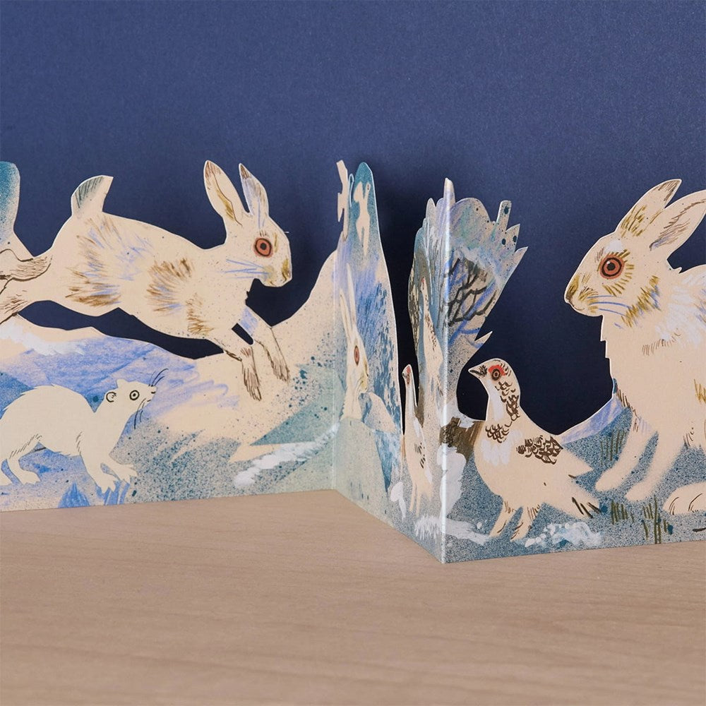 Art Angels close up of front section of die cut card showing bunnies and  other wildlife in winter scene.