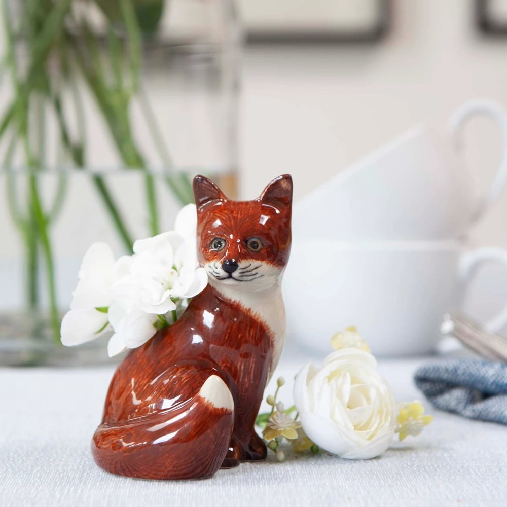 Lifestyle shot of Quail Ceramics Fox Bud Vase (1 pc) with white flowers in the vase and white flowers next to vase