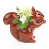 Quail Ceramics Squirrel Bud Vase (1 pc) shown side view with green foliage and white flowers in the vase