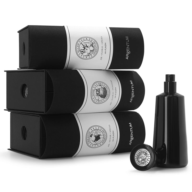 3 Argentum fragrance boxes beside a fragrance bottle with cap off