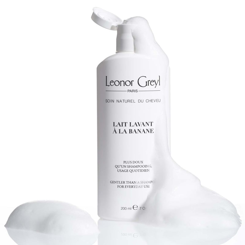 Lifestyle shot of Leonor Greyl Lait Lavant a la Banane Shampoo (200 ml) with soap suds around bottle