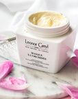 Lifestyle shot of Leonor Greyl Masque A L'Orchidee (200 ml) with lid off showing color and texture of the masque and pink petals in the background