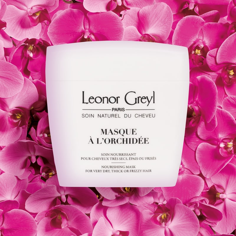 Lifestyle shot top view of Leonor Greyl Masque A L&#39;Orchidee (200 ml) with pink orchid flowers in the background