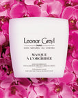 Lifestyle shot top view of Leonor Greyl Masque A L'Orchidee (200 ml) with pink orchid flowers in the background