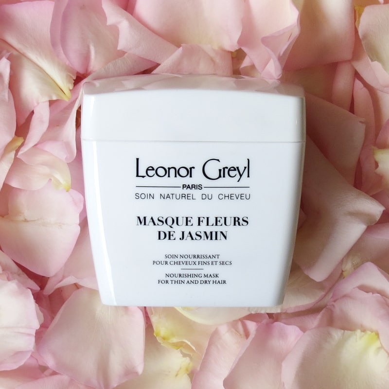 Lifestyle shot top view of Leonor Greyl Masque Fleurs de Jasmin Jasmine Conditioner (200 ml) with pink rose petals in the background