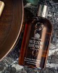 Lifestyle shot of Molton Brown Re-charge Black Pepper Bath & Shower Gel (300 ml) with marble background