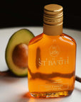 Lifestyle shot of Ligne St. Barth Avocado Oil (6.8 oz) with avocado in the background