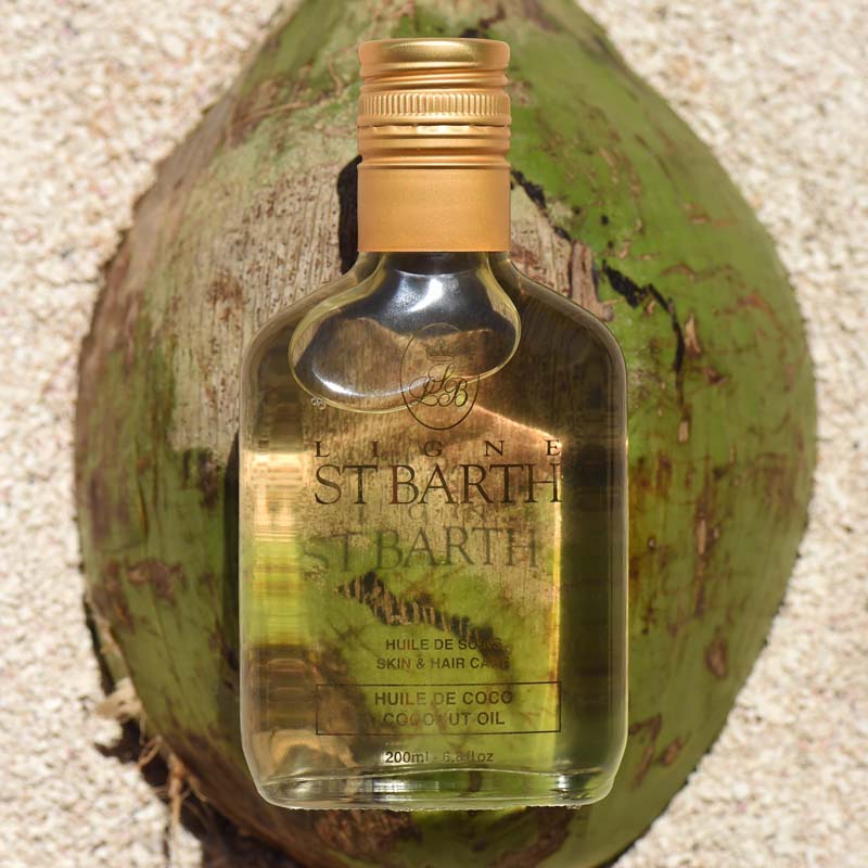 Lifestyle shot of Ligne St. Barth Coconut Dry Oil (6.8 oz) on top of a green coconut