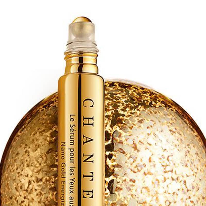 Close up shot of Chantecaille Nano Gold Energizing Eye Serum (15 ml) with top off showing roller ball head and golden globe in the background
