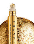 Close up shot of Chantecaille Nano Gold Energizing Eye Serum (15 ml) with top off showing roller ball head and golden globe in the background