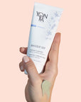 Model holding tube of Yon-Ka Paris Masque 103 (75 ml) with smear of mask on her hand to show color and texture