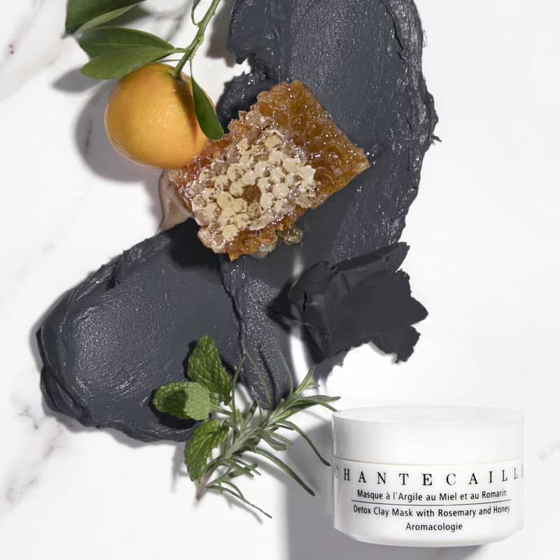Top view beauty shot of Chantecaille Detox Clay Mask with Rosemary &amp; Honey (50 ml) showing rosemary, piece of honeycomb, orange and smear of mask to show color and texture 