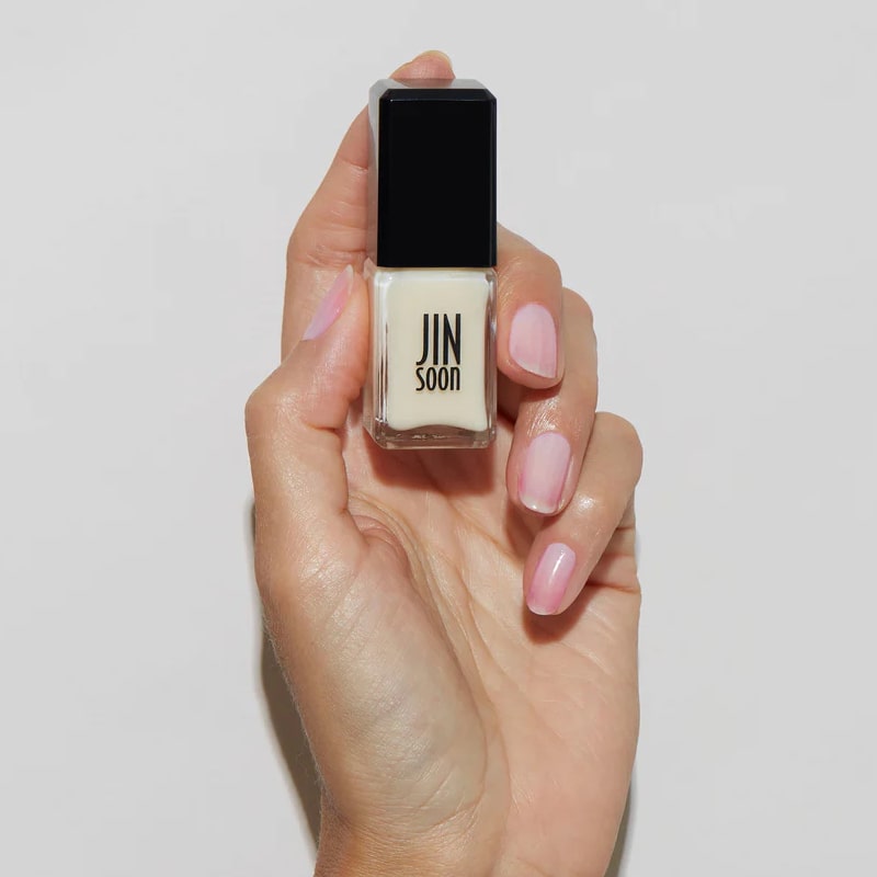Model with light skin tone wearing and holding bottle of JINsoon Nail Lacquer - Tulle