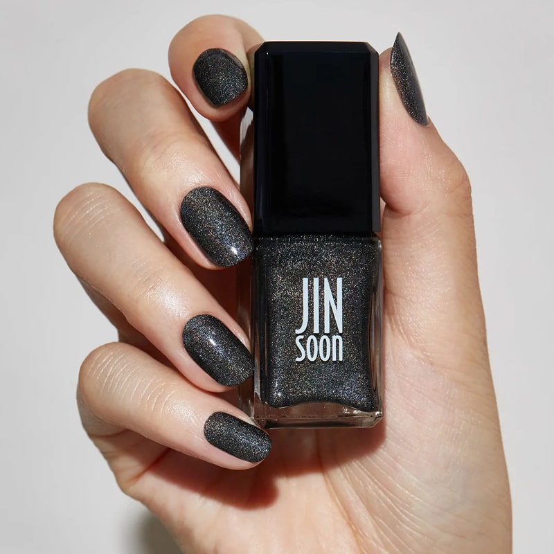 Model with light skin tone wearing and holding bottle of JINsoon Nail Lacquer - Mica