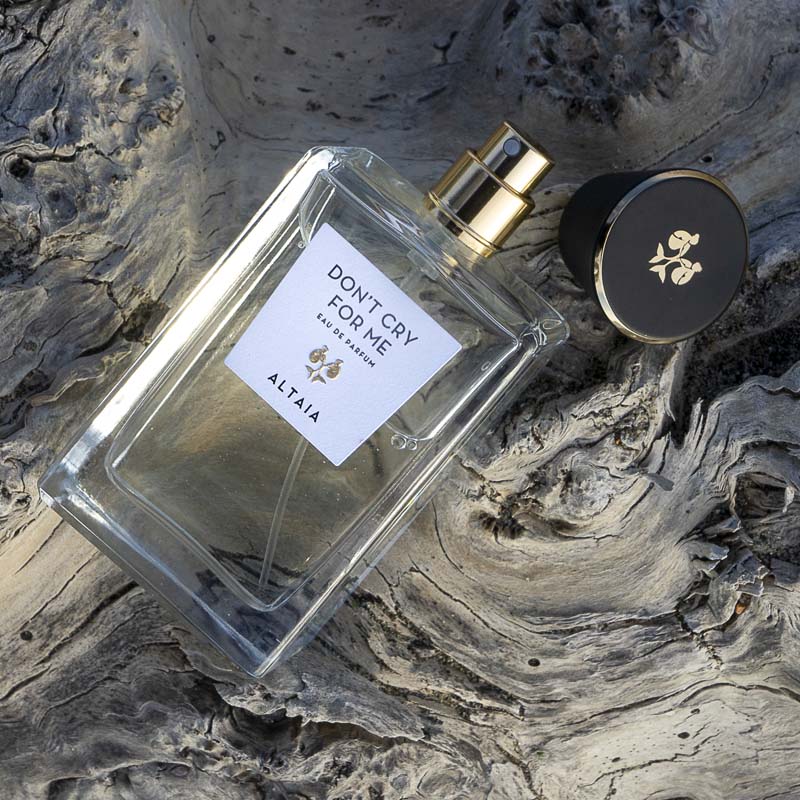 Beauty shot of ALTAIA Don't Cry For Me Eau de Parfum with cap off and wood in the background