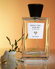 Beauty shot of ALTAIA Don't Cry For Me Eau de Parfum with white flower in the foreground and orange background