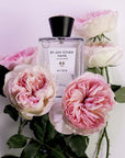 Beauty shot of ALTAIA By Any Other Name Eau de Parfum with pink roses in the background