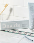 Beauty shot of Davids Premium Natural Toothpaste (5.25 oz) on sink top with brushes