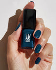 Model with light skin tone wearing and holding bottle of JINsoon Nail Lacquer - Beau