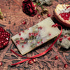 Lifestyle shot of Santa Maria Novella Melograno Scented Wax Tablet with pomegranate and red rose in the background