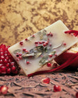 Lifestyle shot of Santa Maria Novella Melograno Scented Wax Tablet with pomegranate in the background