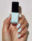 Model with light skin tone wearing and holding bottle of JINsoon Nail Lacquer - Peace