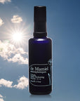 de Mamiel Exhale Daily Hydrating Nectar (50 ml) with blue sky, clouds and sun in the background