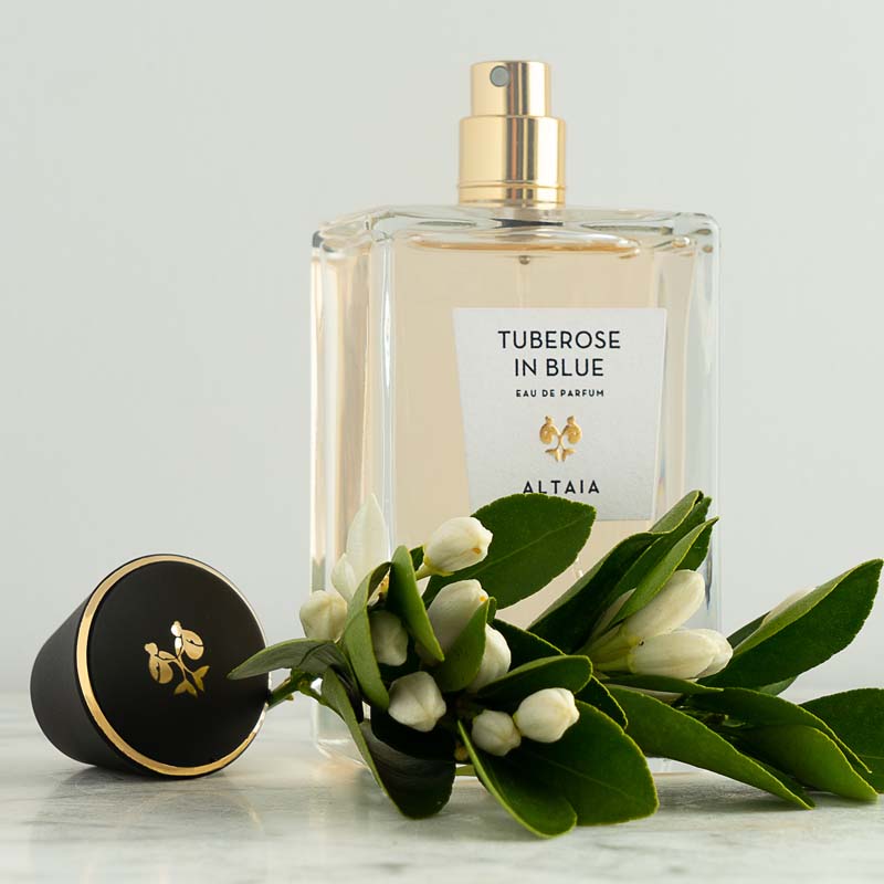Beauty shot of ALTAIA Tuberose in Blue Eau de Parfum with top off and tuberose flowers in the foreground