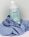 Lifestyle shot of Kerzon Fragranced Laundry Soap - Super Frais (33.34 oz) with denim in the background