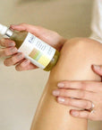 Esker Beauty Restorative Oil (4 oz) shown with model applying to leg