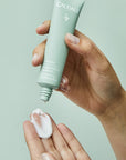 Lifestyle shot of Caudalie Vinopure Moisturizing Mattifying Fluid (40 ml) tube in hand of model and cream on fingertips