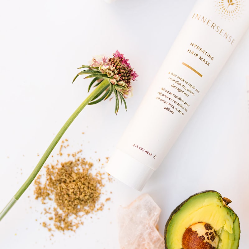Lifestyle shot of Innersense Organic Beauty Hydrating Hair Masque 4 oz with flower, avocado and crystal in the background